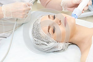 Microcurrent facial dermatology procedure. Model. Aesthetic radiofrequency treatment. Micro current cosmetology massage photo
