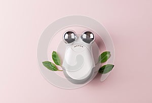 microcurrent facial toning device on pink background with green leaves