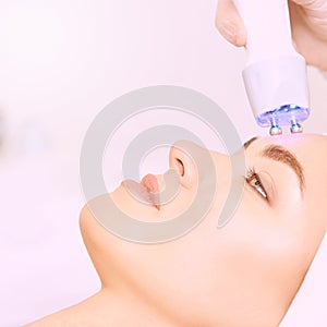 Microcurrent light esthetics procedure. Beauty girl face. Cosmetology machine. Doctor hands. Two micro balls. Wrinkle reduction