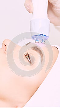 Microcurrent light esthetics procedure. Beauty girl face. Cosmetology machine. Doctor hands. Two micro balls. Wrinkle reduction