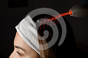 Microcurrent massage of a woman& x27;s head on a dark background