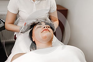 Microcurrent therapy. Cosmelotologist makes stimulating facial massage with electric gloves. Lymphatic drainage massage