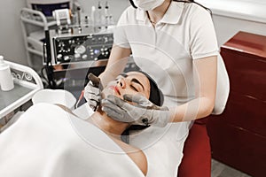 Microcurrent therapy. Cosmelotologist makes stimulating facial massage with electric gloves. Lymphatic drainage massage