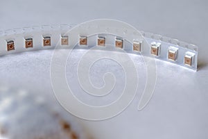 Microelectronic Industry Concepts. Closeup of Tape with SMD or Surface Mount Inductance Components in Tape Together On White