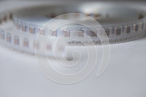 Microelectronics Ideas. Closeup of Tape with SMD or Surface Mount Inductance Components in Tape Together On White photo