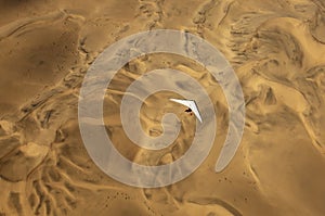 A microlight aircraft can be seen flying over the sands of Namibia