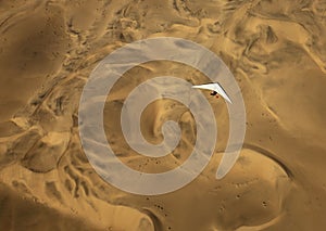 A microlight aircraft can be seen flying over the sands of Namibia