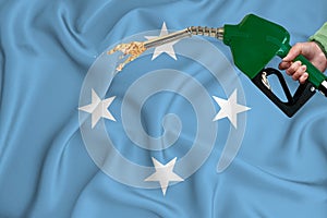 MICRONESIA flag Close-up shot on waving background texture with Fuel pump nozzle in hand. The concept of design solutions. 3d
