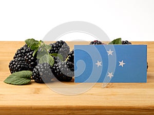 Micronesian flag on a wooden panel with blackberries isolated on photo