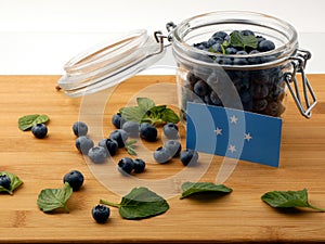 Micronesian flag on a wooden plank with blueberries on photo