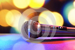 Microphone on black table and colored lights background