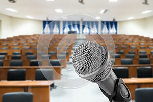 Microphone with blurred photo of empty conference hall or seminar room in background. Business meeting concept