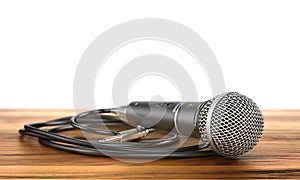Microphone with cable on a wood background.