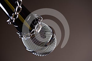 Microphone with a chain, depicting the idea of freedom of the press or freedom of expression on dark background. World press