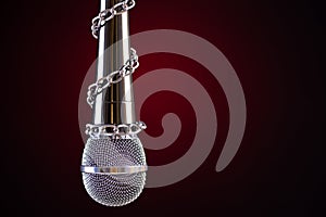 Microphone with a chain, depicting the idea of freedom of the press or freedom of expression on dark background. World press