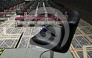 Microphone on chair and rows of chairs in grand conference hall