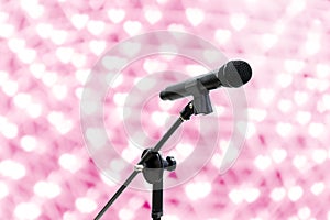 Microphone close up shot on blur heart bokeh Pink background beautiful romantic or glitter lights heart soft pastel shade