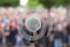 Microphone in focus against blurred crowd. Political rally.