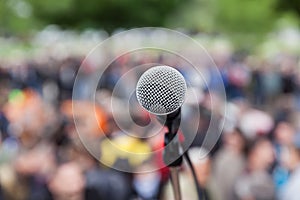 Microphone in focus against blurred crowd. Protest.