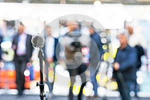 Microphone in focus against blurred journalists, reporters and camera operators at news conference or media event. Public