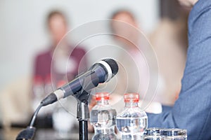 Microphone in focus against blurred people at roundtable event