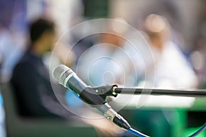 Microphone in focus against blurred people at roundtable event