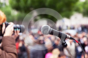 Microphone in focus, blurred female photographer at work in the background