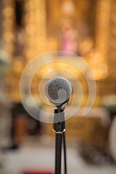 Microphone in the foreground ready to be used inside a church or religious space. Blurred church background