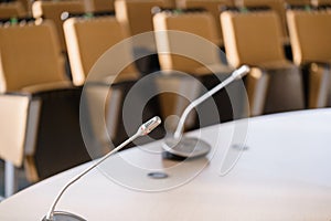 Microphone in the foreground. Seminar presentation. Conference room full of empty seats. Red color. Hall for workshops