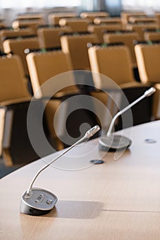 Microphone in the foreground. Seminar presentation. Conference room full of empty seats. Red color. Hall for workshops