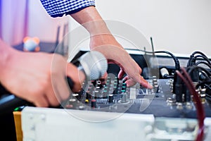 Microphone in hand and adjust an audio mixer controller in the control room, Sound mixer control for live music and studio
