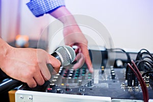 Microphone in hand and adjust an audio mixer controller in the control room, Sound mixer control for live music and studio