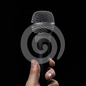 Microphone in hand on a black background, close-up.