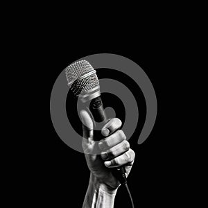 Microphone in hand on a black background, close-up.