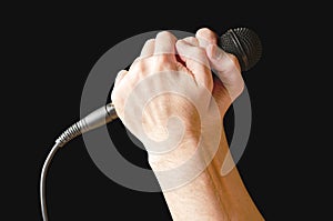 Microphone in hand closeup. Isolated on a black background