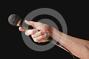 Microphone in hand closeup. Isolated on a black background