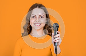 microphone in hand of teen girl on yellow background. selective focus