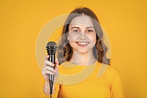 microphone in hand of teen girl on yellow background. selective focus