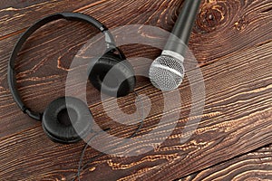 Microphone and headphones on brown wooden background.
