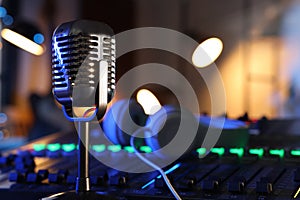 Microphone near professional mixing console and headphones in radio studio