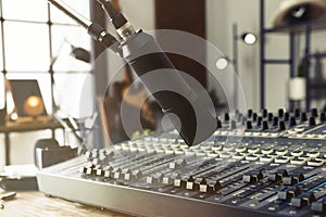 Microphone near table with professional mixing console in radio studio, closeup