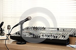 Microphone and professional mixing console on wooden table in radio studio