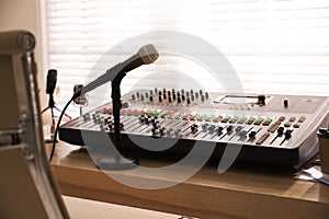 Microphone and professional mixing console on wooden table in radio studio