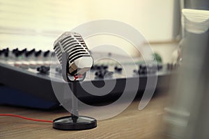 Microphone and professional mixing console on wooden table in radio studio