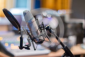 Microphone in a professional recording or radio studio, equipment in the blurry background