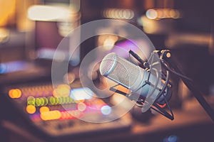 Microphone in a professional recording or radio studio, equipment in the blurry background