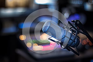 Microphone in a professional recording or radio studio, equipment in the blurry background