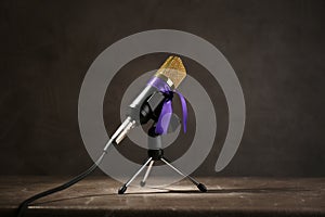 Microphone with purple awareness ribbon on table against dark background