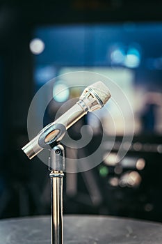 Microphone in the recording studio, equipment and lighting in the blurry background
