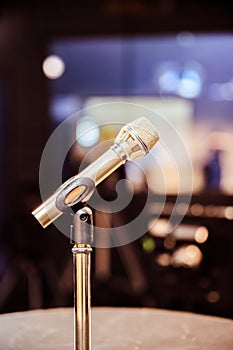 Microphone in the recording studio, equipment and lighting in the blurry background